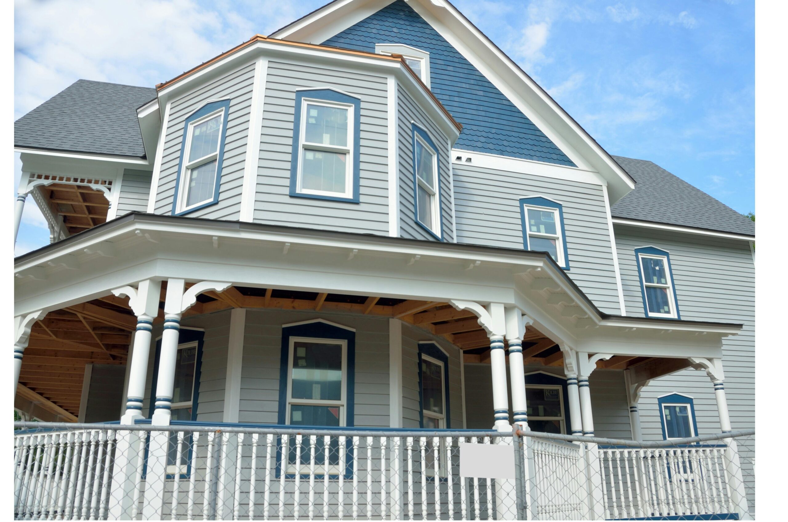 Charming Victorian-style home with gray wood siding and blue accents seen from the street.